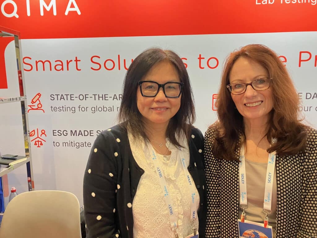 Belle and Karolyn in the QIMA testing lab booth at ICPHSO 2026