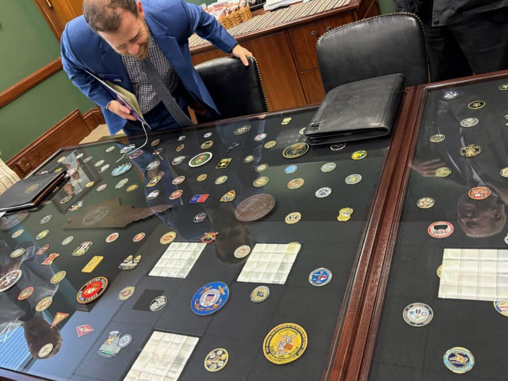 man looks at display full of commemorative challenge coins